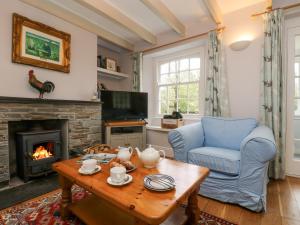 a living room with a fireplace and a blue chair at Trenouth Cottage in Padstow