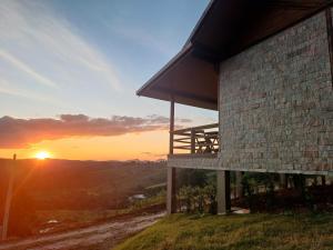 a building on a hill with the sunset in the background at Chalé Estância do Lagarto in Domingos Martins