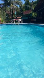 ウバトゥバにあるGuest House Santiagoの2つの白い椅子が置かれた青い水の大きなプール