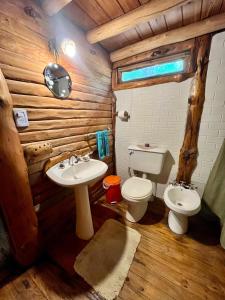 a bathroom with a toilet and a sink in a log cabin at NOMADE cabin rent in San Antonio de Arredondo +23 photos