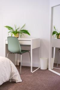 a white desk with a green chair and a mirror at Aura Room - Kingsize minimalist room in Luton in Luton