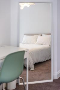 a bedroom with a bed and a chair and a mirror at Aura Room - Kingsize minimalist room in Luton in Luton