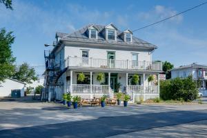 a white house with a porch and tables on the street at Chambre 304 de l'hôtel Victoria confortable et moderne in Saint-Pascal