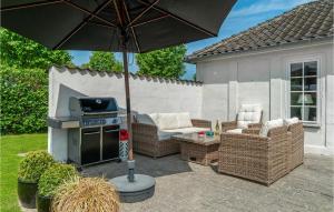 a patio with an umbrella and a grill and chairs at 3 Bedroom Gorgeous Home In Ebeltoft in Ebeltoft