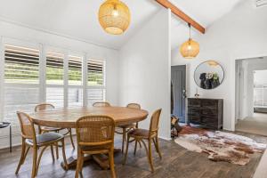 Un comedor con mesa y sillas de madera. en Ekhaya Homestead Berry, en Wattamolla