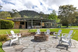 un patio con sillas blancas y una hoguera en Ekhaya Homestead Berry, en Wattamolla