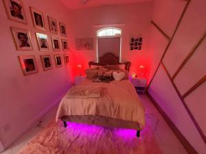 a pink bedroom with a bed with purple lights at The Swift Lake House in Somerset