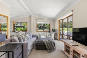 Una sala de estar con un sofá y un televisor. en Ekhaya Homestead Berry, en Wattamolla