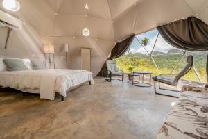 1 camera da letto in una tenda con letto e sedie di Unique Glamping Experience & Romantic Dome with Nature Escape and River a Jaguas