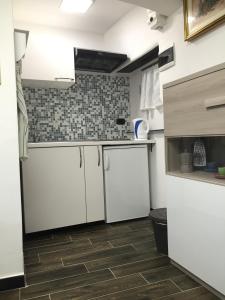 una cucina con armadietti bianchi e pavimento piastrellato di Appartamento al Ponte Reale a Genova