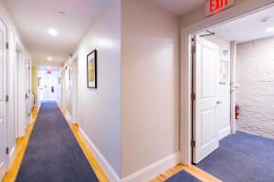 a hallway with white walls and a blue carpet at West Broadway Quarters by Thatch in Boston