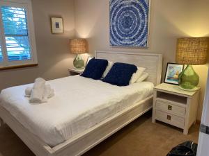 a bedroom with a white bed with blue pillows at The Quindy, family beach house in Quindalup
