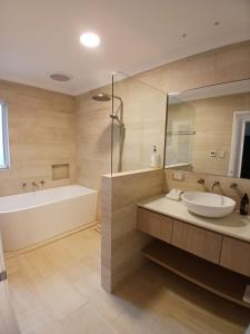 a bathroom with a tub and a sink and a bath tubermott at The Quindy, family beach house in Quindalup +18 photos