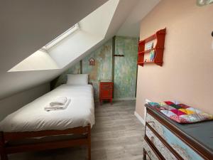 una piccola camera mansardata con letto e cassettiera di Sous les toits de la Tavarn Ty Gar a Hennebont