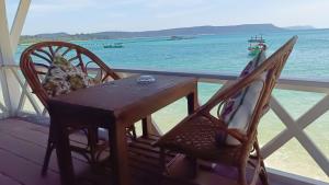 瓜隆岛Paradiso Ocean front Bungalows的门廊上的一张桌子和几把椅子，可以看到海景