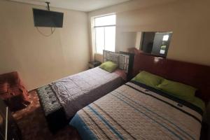 une chambre avec deux lits et un miroir dans l'établissement Depawanka 3 Departamento amoblado y equipada, à Huancayo