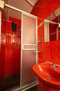 La salle de bains rouge est pourvue d'un lavabo et d'une douche. dans l'établissement Depawanka 3 Departamento amoblado y equipada, à Huancayo