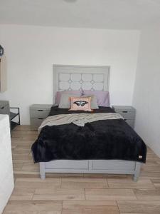 a bedroom with a bed with a black blanket on it at Casita azul in Morelia +5 photos