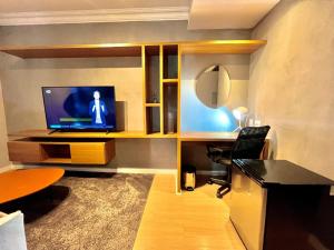 a room with a desk with a laptop and a television at Flat Premium Faria Lima in São Paulo