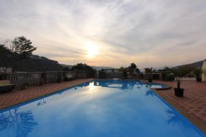 a large swimming pool with a sunset in the background at Mount View Executive in Panchgani