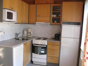 una piccola cucina con elettrodomestici bianchi e armadietti in legno di Koli Country Club a Kolinkylä