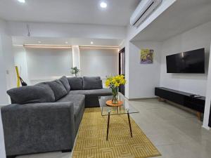 ein Wohnzimmer mit grauem Sofa und einem Fernseher in der Unterkunft Hermoso Apartamento 2 recámaras L4 in Puerto Vallarta
