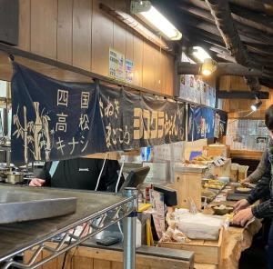 two people standing in a kitchen preparing food at 香川のゲストハウスFDroom in Takamatsu