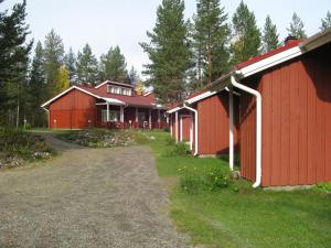 a row of red barns with trees in the background at Koli Country Club in Kolinkylä