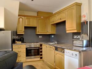 a kitchen with wooden cabinets and stainless steel appliances at Brackendale Cottage - Uk1335 in Threlkeld