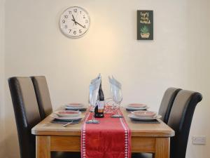 a table with plates and wine glasses and a clock at Brackendale Cottage - Uk1335 in Threlkeld