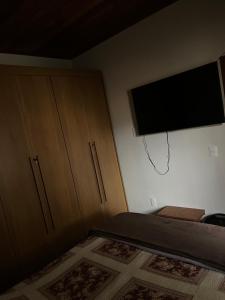 a bedroom with a bed and a flat screen tv at Casa Almeida in Tiradentes