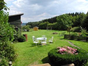 a garden with a table and chairs in the grass at Villa Luzia in Meuspath