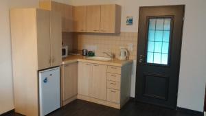 eine kleine Küche mit einem weißen Kühlschrank und einer Tür in der Unterkunft Greek Relaxation in Ma‘yan Barukh