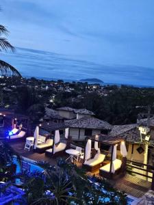 a view of a patio with chairs and tables at night at Apartamento Jardim Geribá in Búzios +35 photos