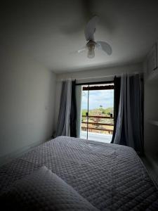 a bedroom with a bed and a window with a view at Apartamento Jardim Geribá in Búzios