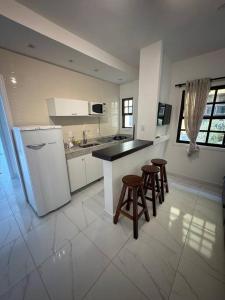 a kitchen with a counter and stools in it at Apartamento Jardim Geribá in Búzios