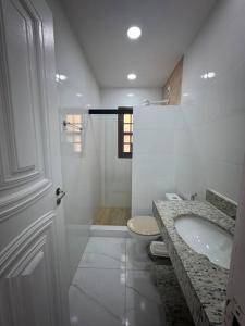 a white bathroom with a sink and a toilet at Apartamento Jardim Geribá in Búzios