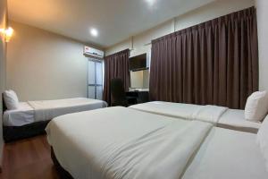 a hotel room with two beds and a desk at Lings Guesthouse in Kuching