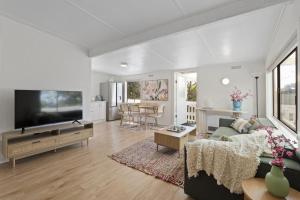 a living room with a couch and a flat screen tv at Blairgowrie Beach Days - beach at end of the street! in Blairgowrie