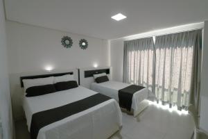 a white bedroom with two beds and a window at Apartamento Familiar II - Vista para o mar e próximo ao Beto Carrero in Penha +22 photos