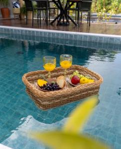 a basket of fruit and wine glasses in a swimming pool at Casa Santorini - Barra Grande - Maraú - Vila Kadosh in Barra Grande