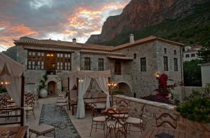 a building with tables and chairs in front of it at Archontiko Hatzipanayioti in Leonidio