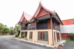 une maison avec un toit en gambrel sur le côté d'une rue dans l'établissement OYO 874 Wong Ruean Thai Resort, à Ban Saen Muang