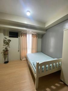a small bedroom with a bed and a window at Condo near ATC- Molito Alabang, Muntinlupa in Manila