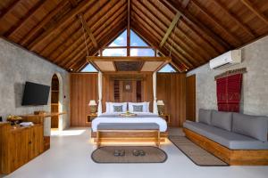 a bedroom with a bed and a couch and a tv at Lasamana Villas Ubud by GenuineHost in Ubud