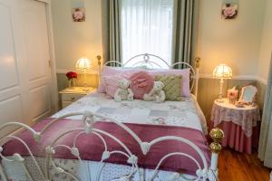 two teddy bears sitting on a bed in a bedroom at Milford Country Cottages in Milford