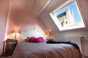a bedroom with a bed with pink pillows and a window at Hotel Le Prieuré et La Résidence in Amiens