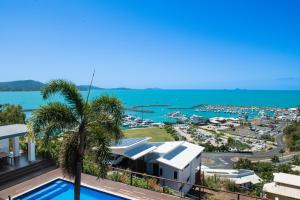 a view of a resort with a palm tree and the ocean at Nautilus On The Hill - Airlie Beach in Airlie Beach
