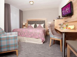バート・クロツィンゲンにあるEden Hotelのベッドとデスクが備わるホテルルームです。