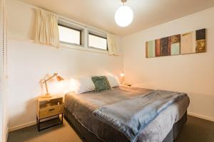 a bedroom with a bed and a lamp on a night stand at Allure Lodge in Paihia
